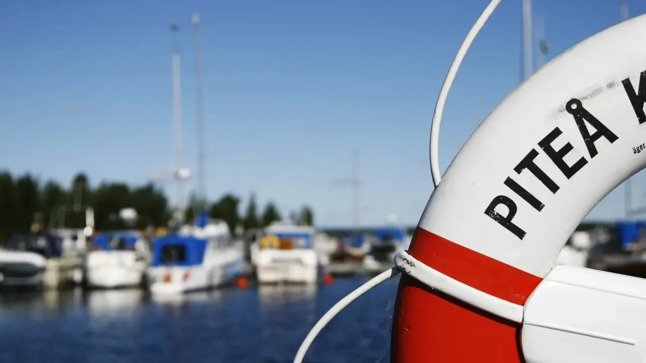 Livboj med texten PITEÅ K visar en hamn med båtar. Ett perfekt ställe att besöka Piteå på!