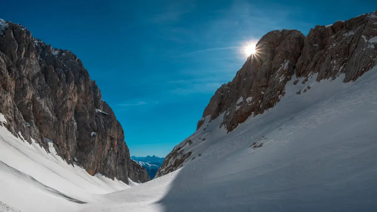 Sole che filtra tra le vette innevate, un invito a scoprire cosa vedere in Friuli Venezia Giulia, tra sentieri e panorami mozzafiato.