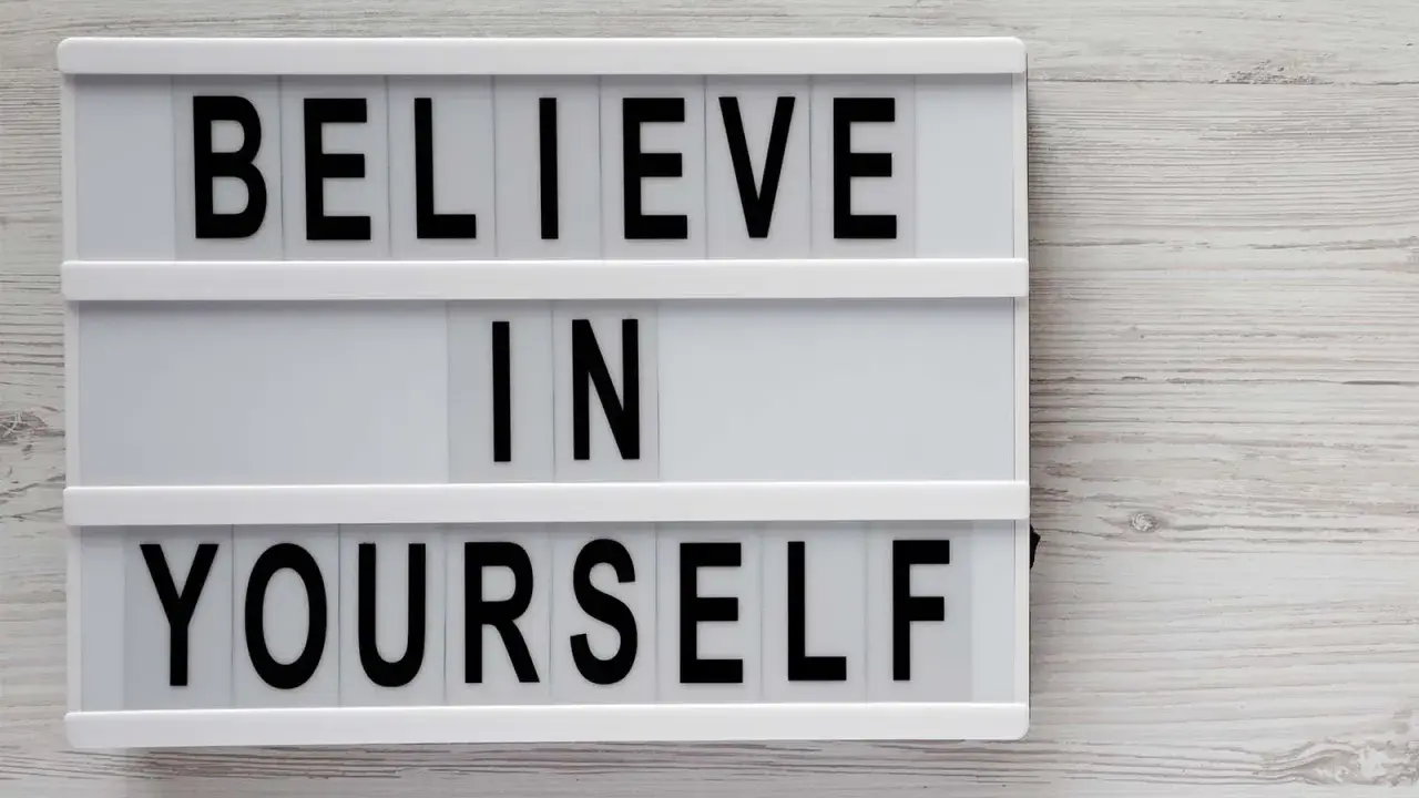 Biała tablica z czarnymi literami: "BELIEVE IN YOURSELF". To przesłanie inspiruje do nastawienia na rozwój i wiary we własne możliwości.