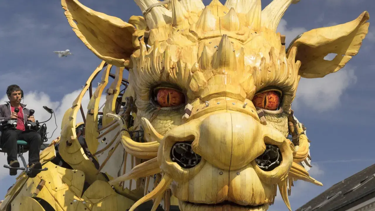 Ein Mann steuert eine riesige Holzdrachen-Skulptur, deren Augen bedrohlich glühen. Die Szene wirkt wie eine Warnung vor drakonischen Strafen, während ein Flugzeug am Himmel vorbeizieht.