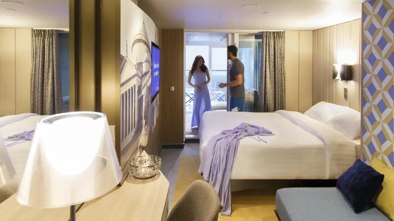 Coppia in una moderna cabina interna di Costa Crociere. Letto matrimoniale, decorazioni artistiche e un balcone invitano al relax.