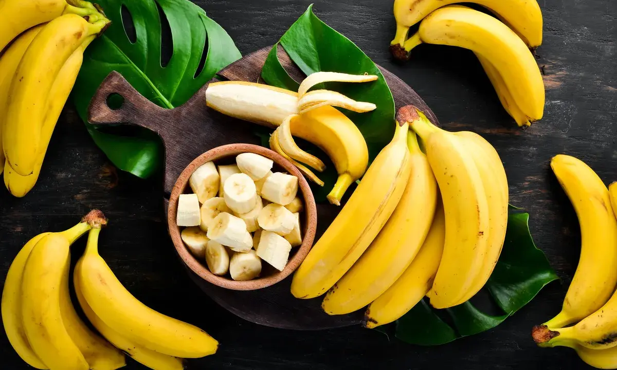 Pęki dojrzałych bananów, jeden obrany i pokrojony w miseczce. Zastanawiasz się, ile węglowodanów ma banan?
