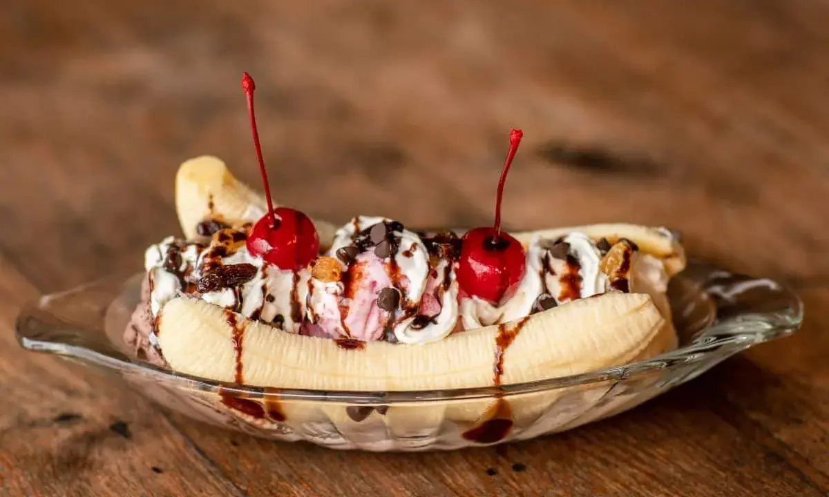 Un déliceux banana split avec glace, crème fouettée, pépites de chocolat et cerises. Une recette parfaite pour un dessert gourmand.