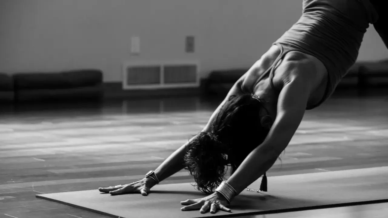 En person utför en nedåtgående hund-position under kundalini yoga.
