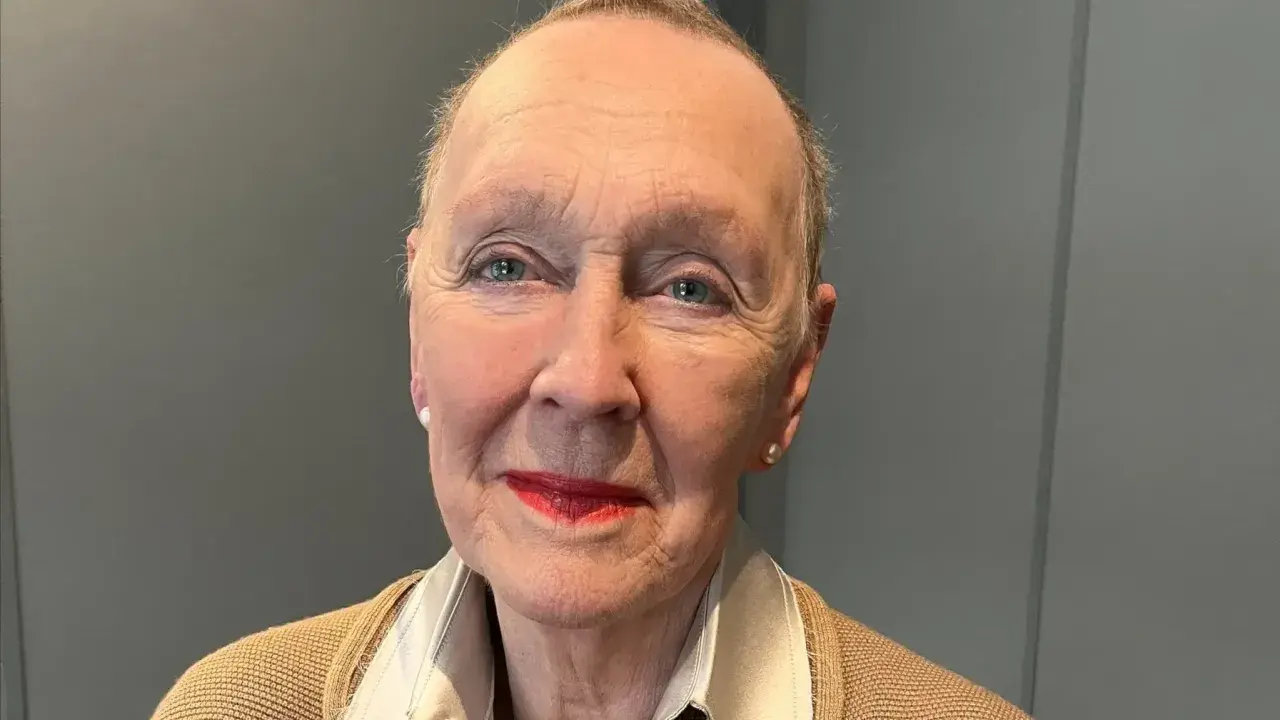 Åldfrun Ebba von Mecklenburg, med sina blå ögon och röda läppar, bär en beige kofta och ett pärlhalsband.
