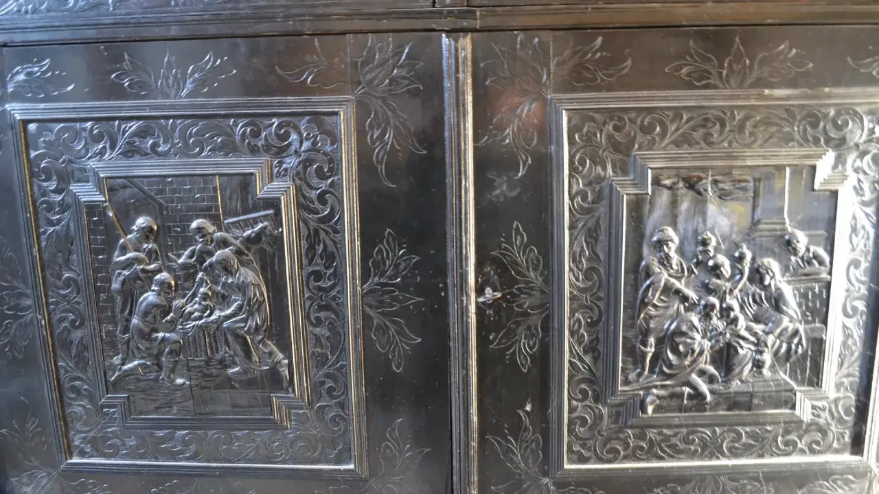 Détail d'un meuble Louis XIII sculpté de scènes bibliques et de motifs floraux.