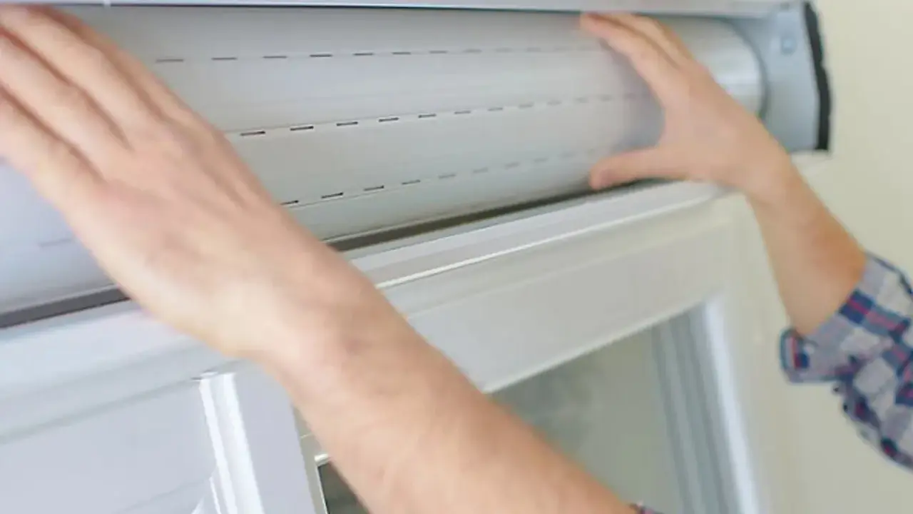 Mains ajustant un volet roulant blanc. Guidez-vous pour savoir comment réparer un volet roulant.