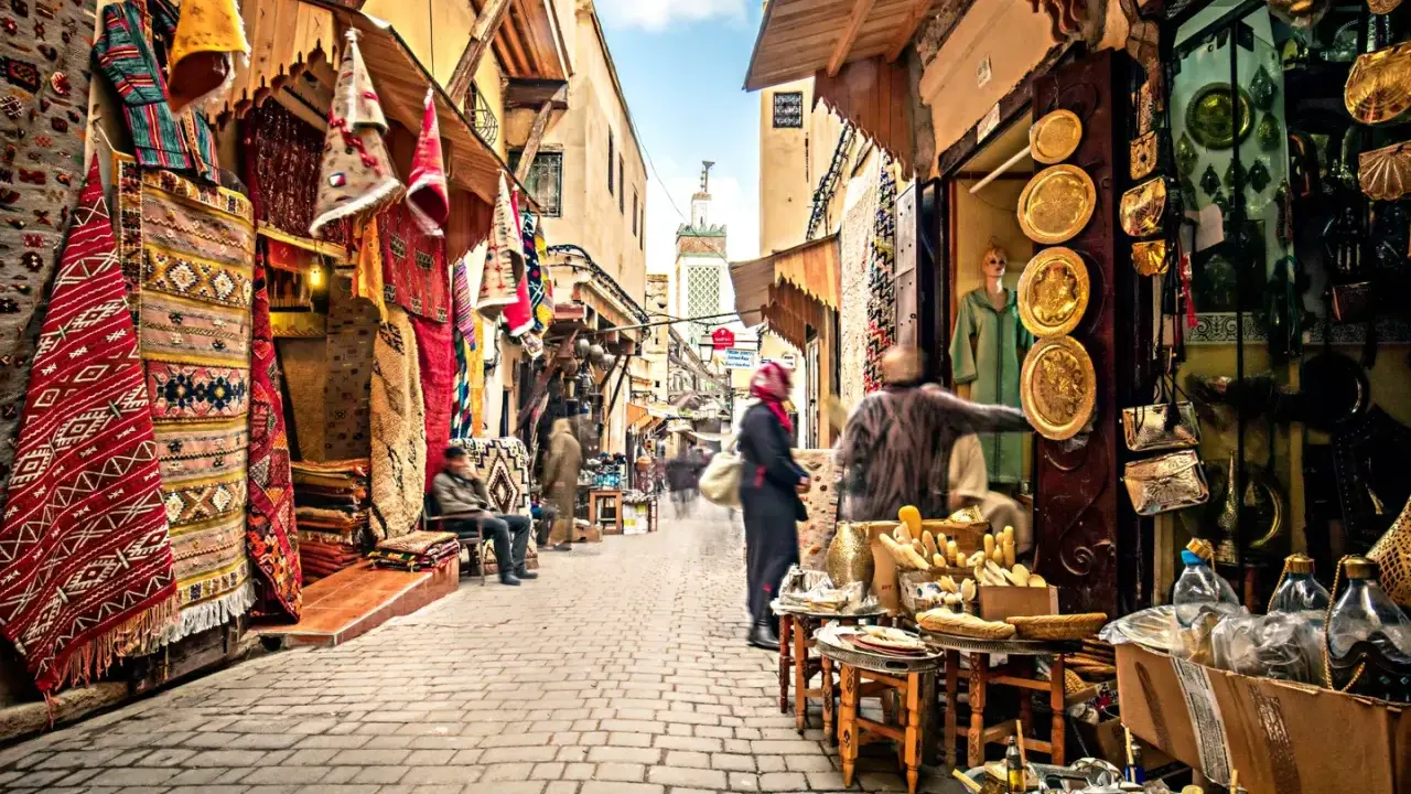 Bunte Teppiche und Souvenirs säumen einen belebten suk markt. Menschen schlendern durch die Gasse, vorbei an Geschäften voller Schätze.