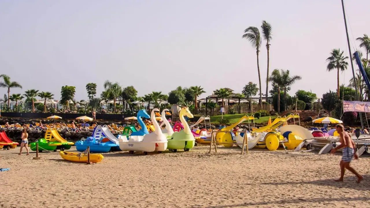 Diversión en Gran Canaria con niños: barcas de pedales con forma de cisne y toboganes esperan en la playa para un día inolvidable.