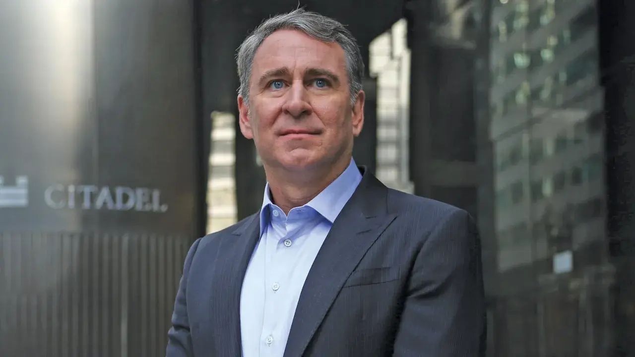 Ken Griffin, w eleganckim garniturze, stoi przed budynkiem z napisem "CITADEL".