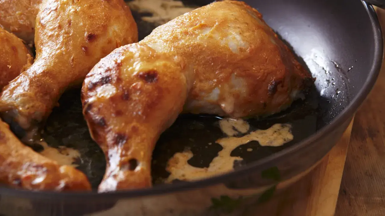 Cosce di pollo dorate e succulente cuociono in padella, emanando un profumo invitante.