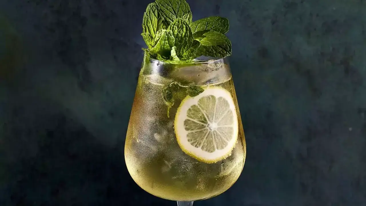 Un verre de Hugo Spritz rafraîchissant, garni de menthe fraîche et d'une tranche de citron. Parfait pour une recette d'été.