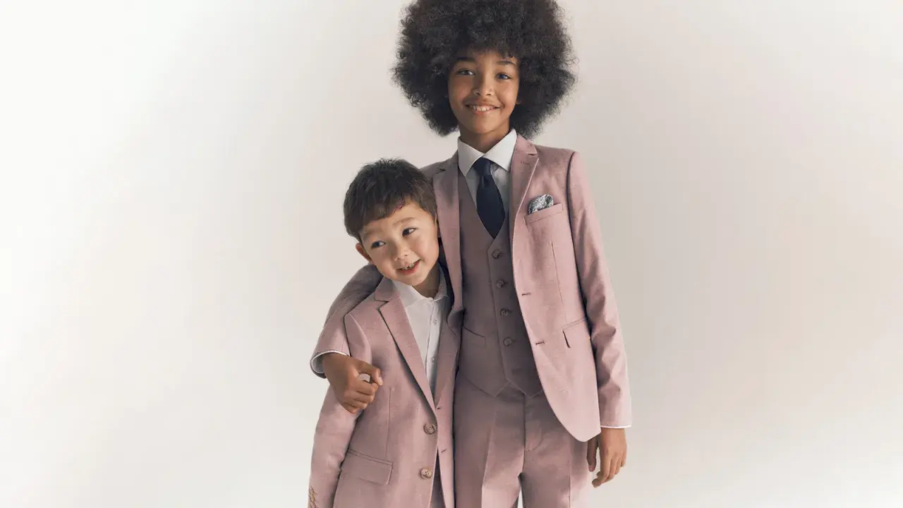 Two boys in matching dusty rose suits, showing what ring bearers wear: tailored jackets, vests, shirts, and ties.
