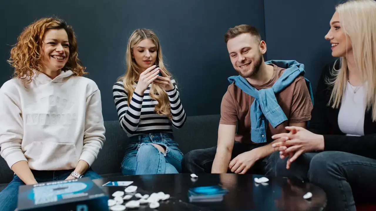 Radosne spotkanie z przyjaciółmi przy planszówce. Uśmiechy, rozmowy i wspólna zabawa.