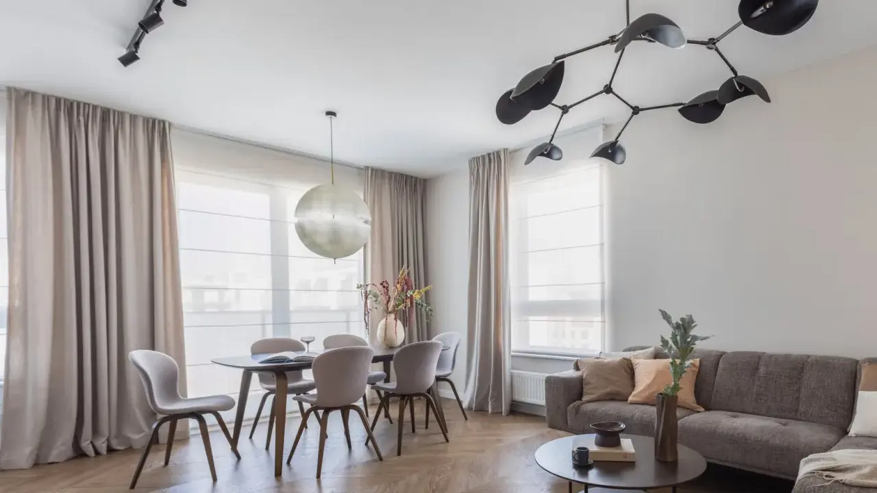 Nowoczesne oświetlenie salonu z jadalnią: designerski żyrandol i reflektory nad stołem. Aranżacje wnętrz z klasą.