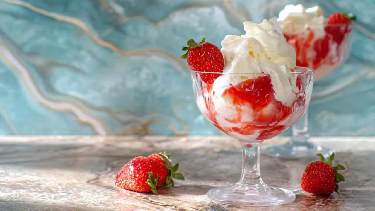 Délicieux dessert fraise melba, glace à la vanille, coulis de fraises et chantilly, garni d'une fraise fraîche.