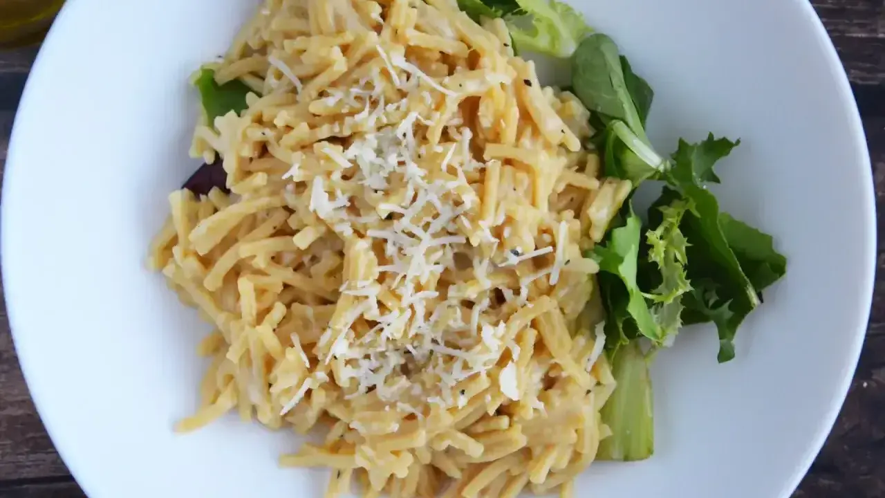 Pyszne cacio e pepe z tartym serem i świeżą sałatką na białym talerzu.