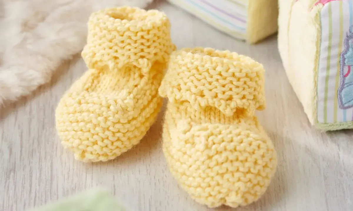 Patucos dos agujas de lana amarilla, perfectos para abrigar los pies de un bebé.