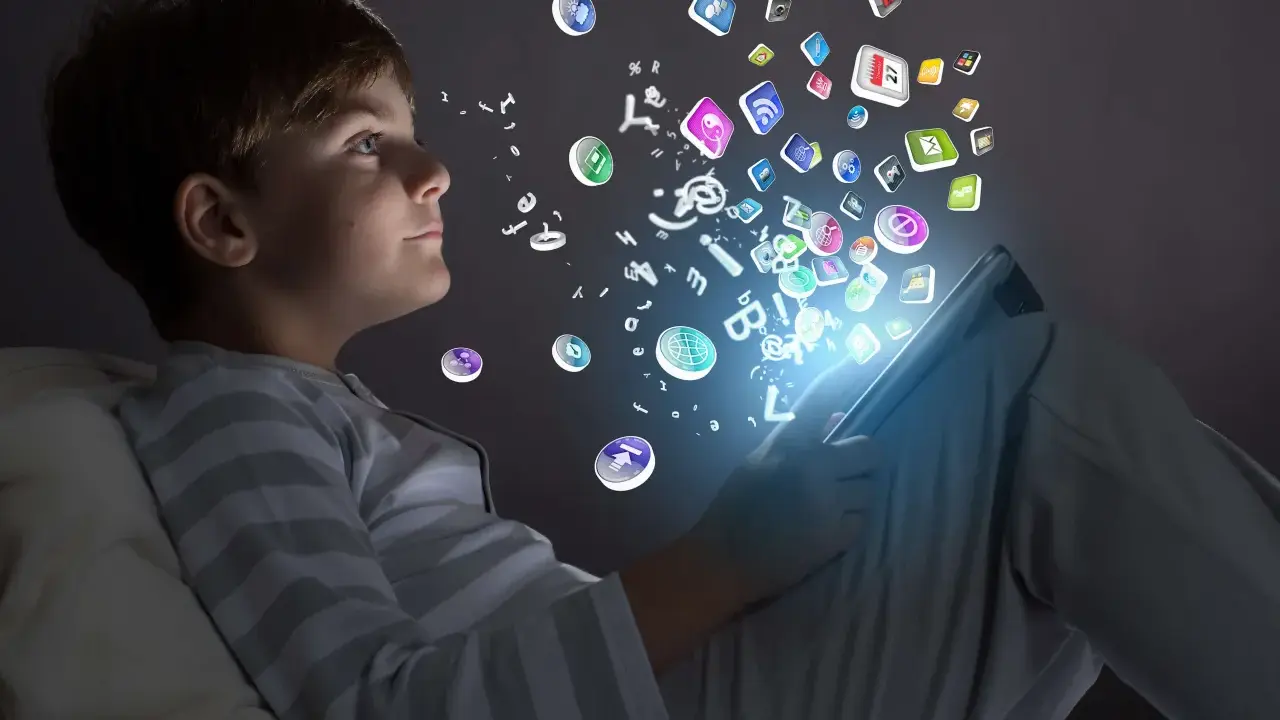 Niño de la generación alfa interactuando con iconos de aplicaciones y letras que flotan desde una tablet.