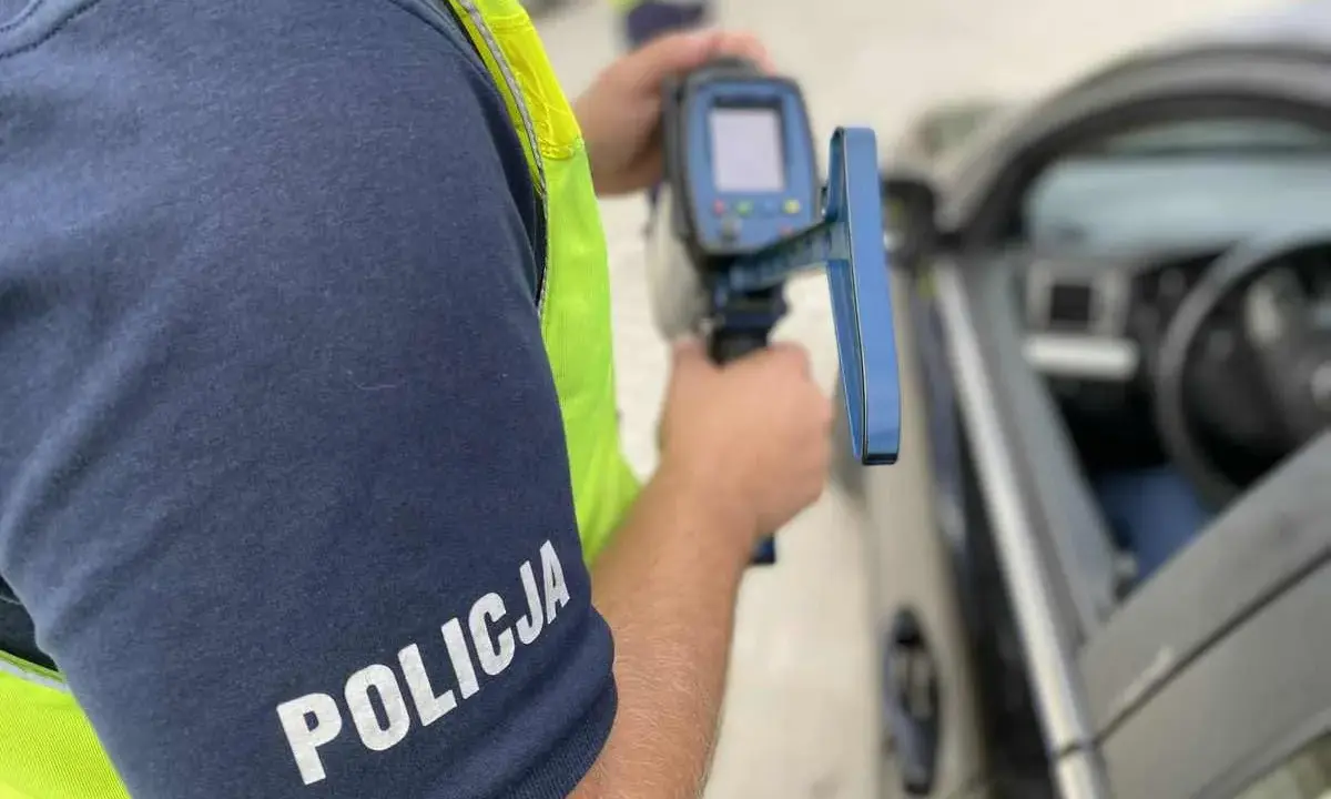 Policjant mierzy prędkość samochodu radarem.