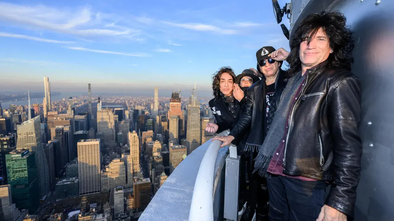 Les membres du groupe KISS posent sur un gratte-ciel new-yorkais, offrant une vue imprenable sur la ville.