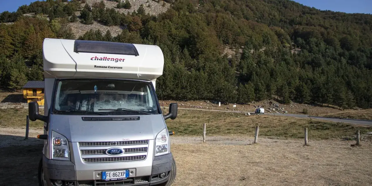 Camper parcheggiato in un'area panoramica della Calabria, con boschi e montagne sullo sfondo. Un'avventura in camper indimenticabile.