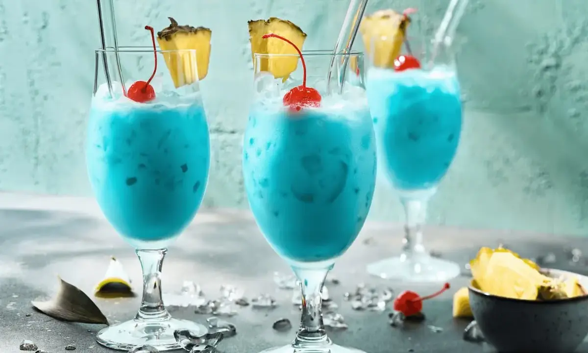 Erfrischende blaue Swimmingpool-Cocktails mit Ananas und Kirschen, bereit für den Sommer.