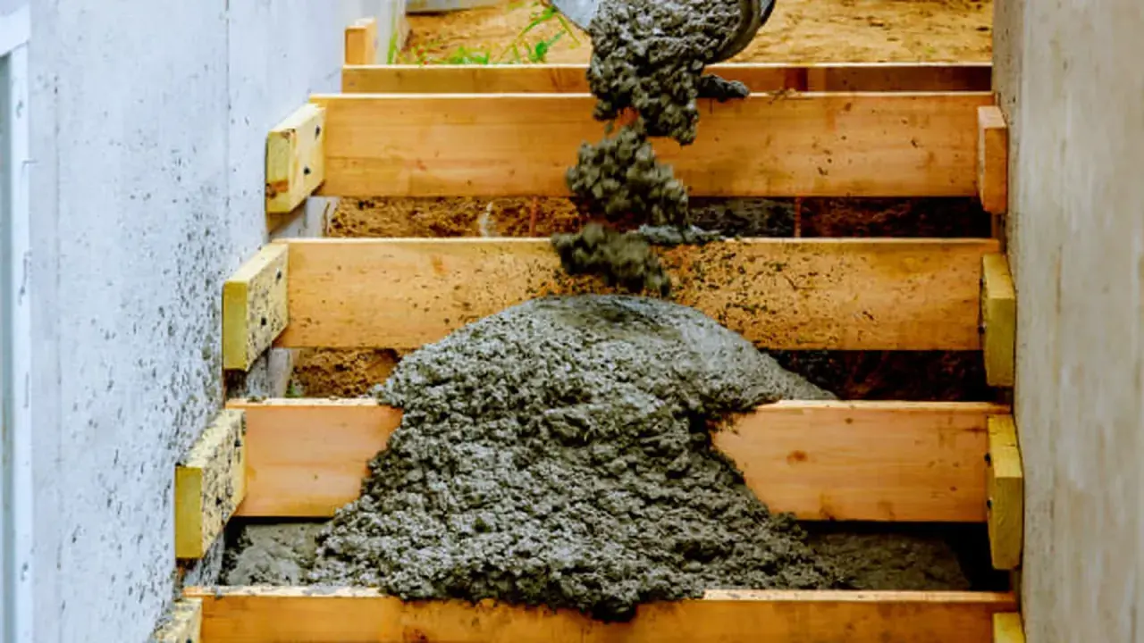 Vertiendo cemento en encofrado de madera para como hacer escalera de obra.
