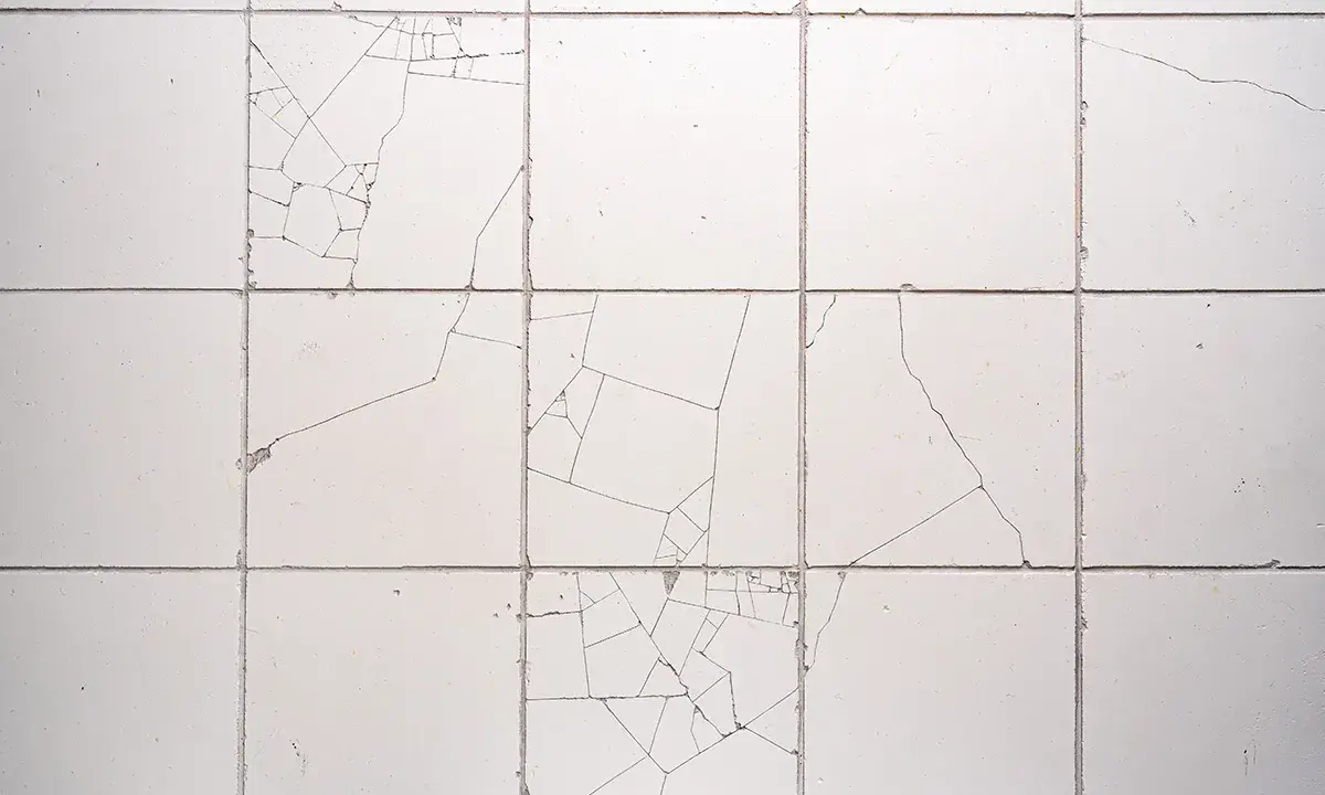 Uszkodzone płytki ceramiczne, widoczne pęknięcia tworzą mozaikę. Reklamacja płytek po położeniu jest konieczna.