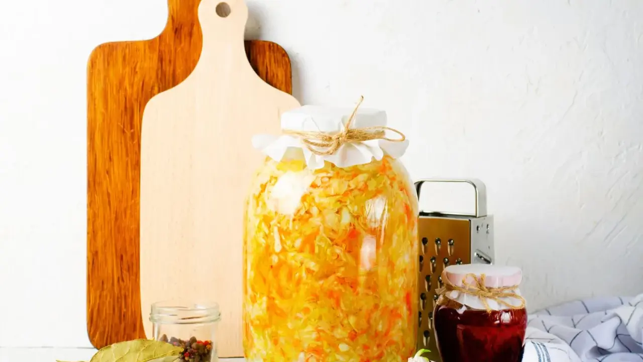 Großes Glas mit Sauerkraut, bereit zum **fermentieren im Schraubglas**. Daneben Gewürze, Knoblauch und ein kleines Glas Marmelade.
