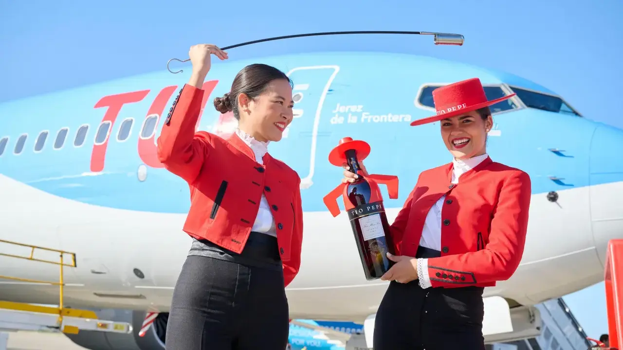 Zwei Frauen in Flamenco-Kleidung am Flughafen Jerez. Eine hält eine Flasche Tio Pepe Sherry, die andere eine Peitsche.