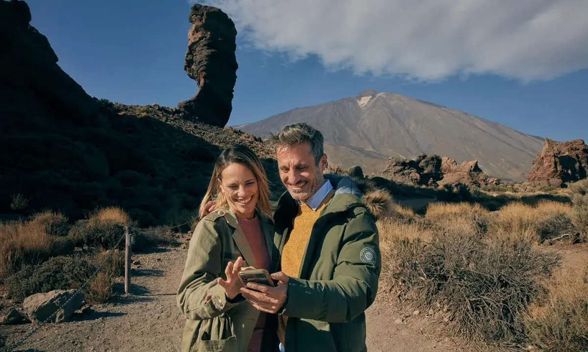 Pareja sonriente en un paisaje volcánico, quizás planeando su visita al museo de la naturaleza y el hombre.