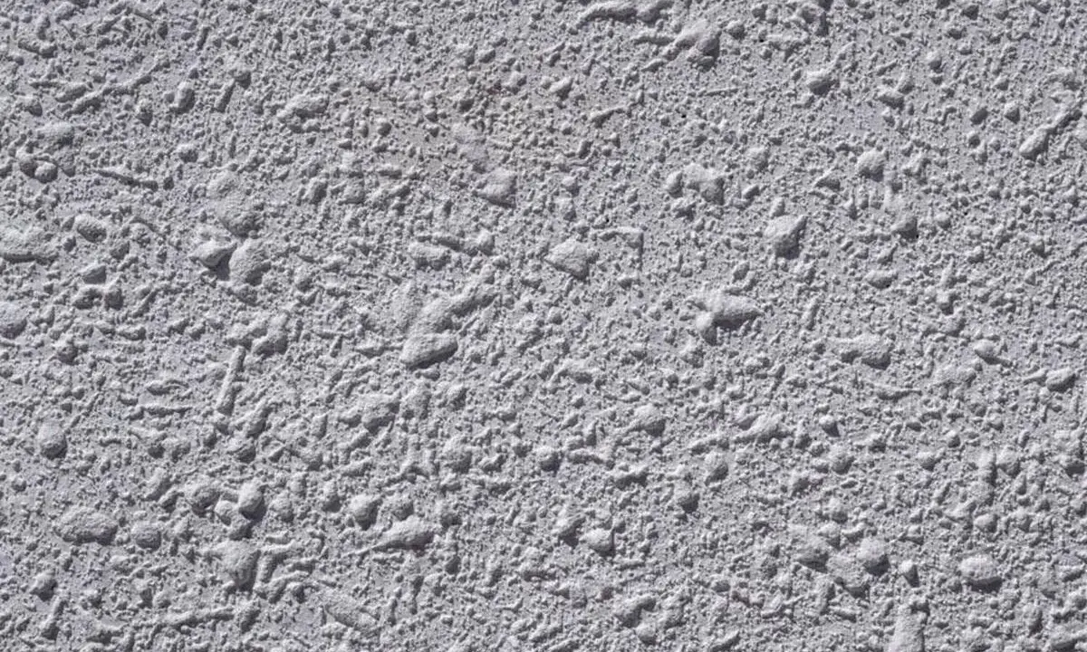 Textura gris de pared con relieve irregular, típica del **el gotelé**, que crea un efecto rugoso y con pequeñas protuberancias.
