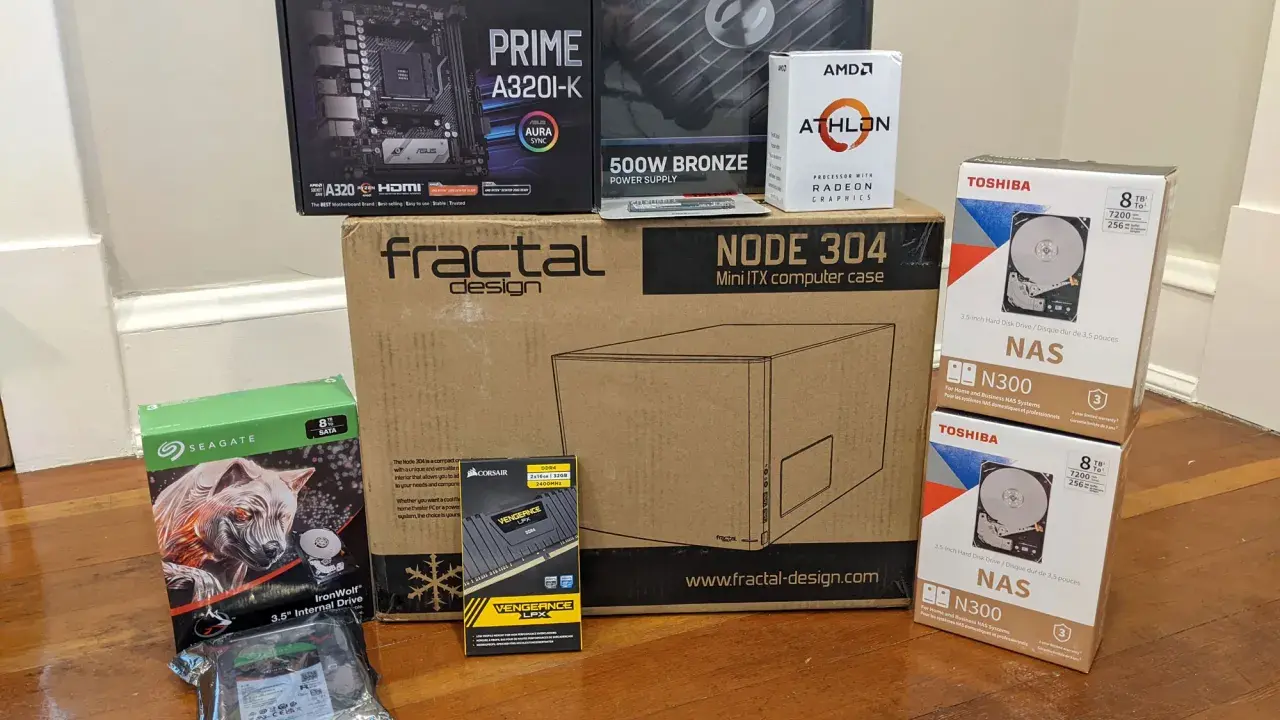 Composants pour installer un NAS : carte mère ASUS, processeur AMD Athlon, boîtier Fractal Design, alimentation, RAM Corsair, et deux disques durs Toshiba 8 To.