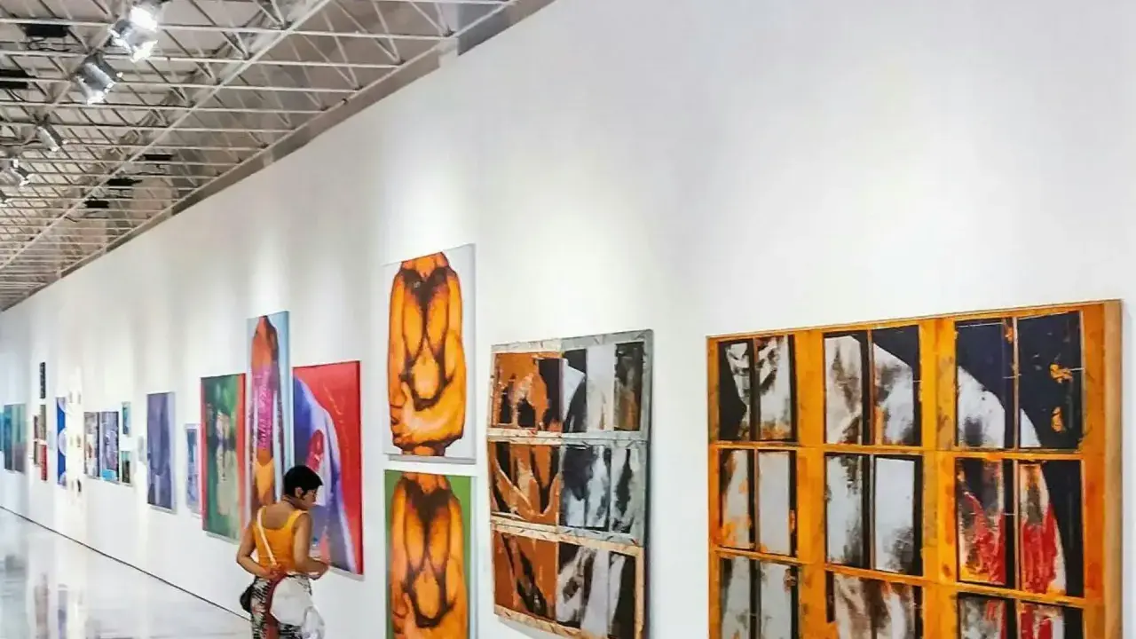 A person views colorful abstract paintings in a modern gallery, a stark contrast to a traditional museum.