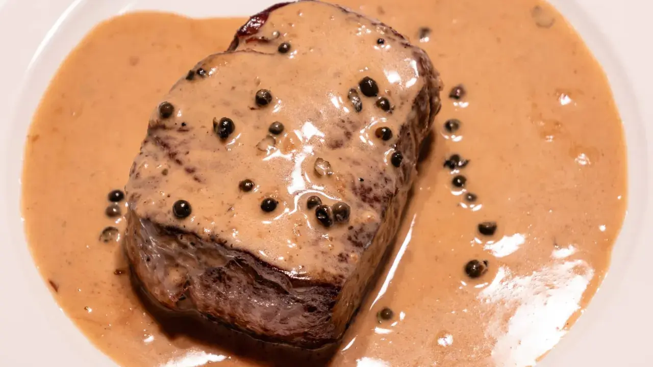 Un steak tendre baignant dans une onctueuse sauce au poivre, parsemée de grains de poivre noir. Un délice pour les yeux et les papilles.