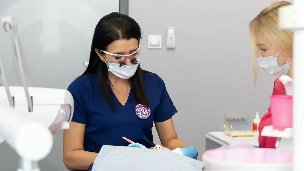 Dentystka w okularach i masce pracuje przy pacjencie. Dyskutują, jak przyspieszyć schodzenie znieczulenia.