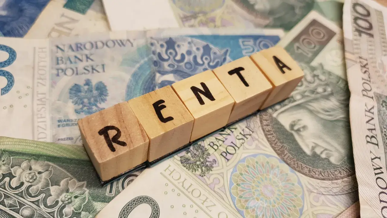 Drewniane klocki z napisem "RENTA" leżą na polskich banknotach.