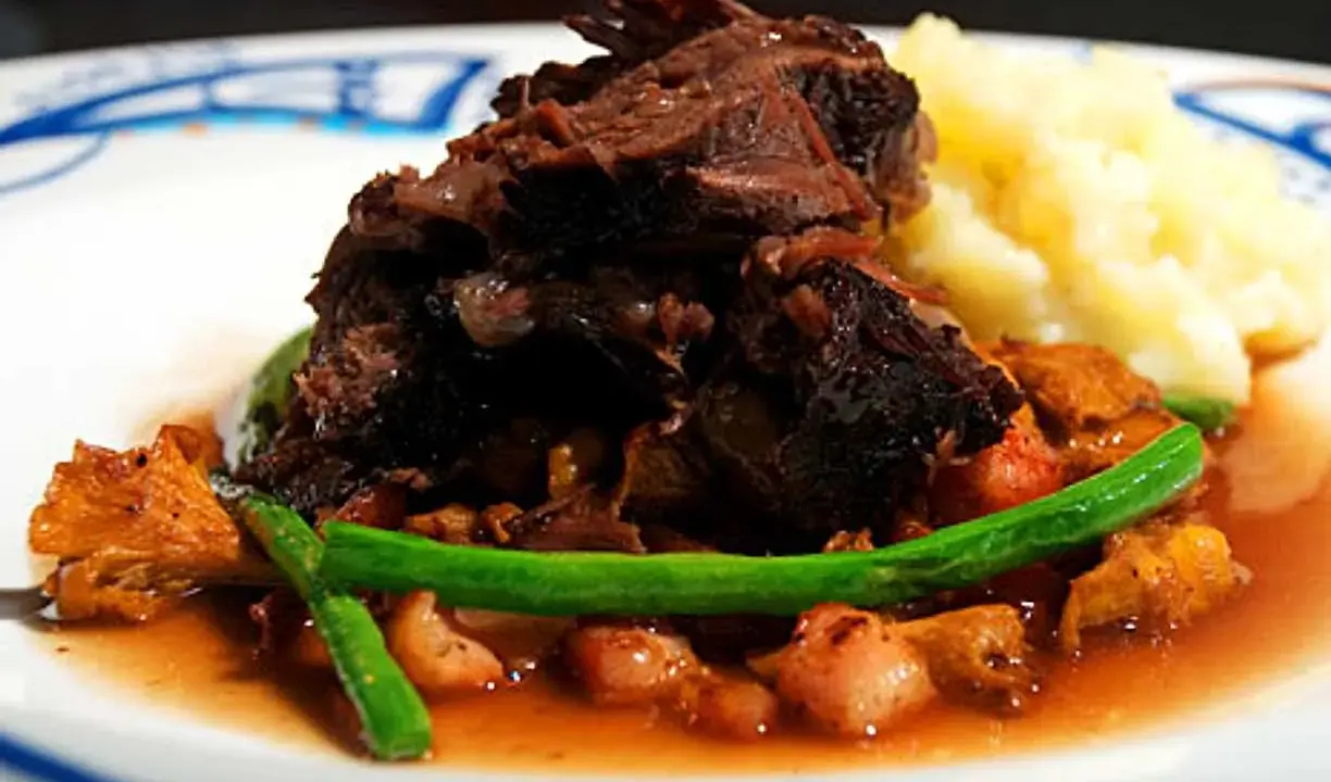 En härlig tallrik med långkokt oxkind, kantareller, gröna bönor och potatismos. Ett perfekt oxkind recept för en festmåltid.