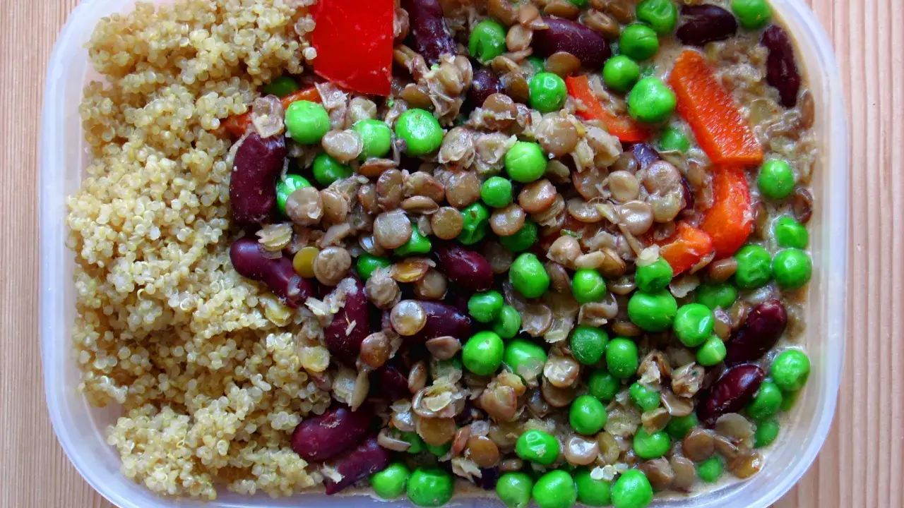 En näringsrik vegetarisk matlåda med quinoa, linser, bönor, ärtor och paprika. Perfekt för en hälsosam lunch.