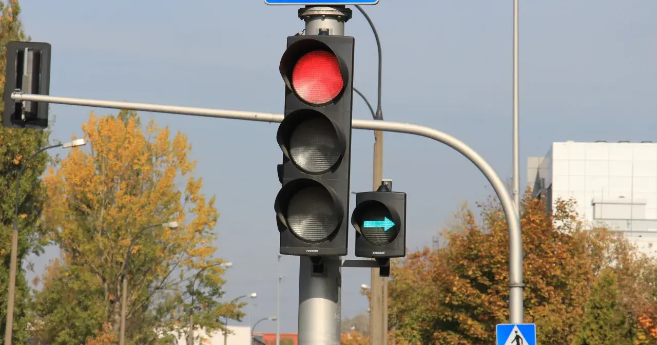 Sygnalizacja świetlna z czerwonym światłem i zielona strzałka wskazująca skręt w prawo.