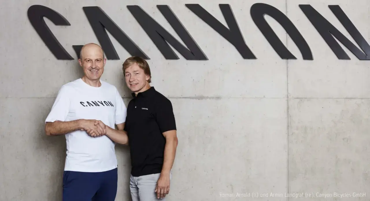 Roman Arnold und Armin Landgraf schütteln sich die Hände vor dem Canyon-Logo.