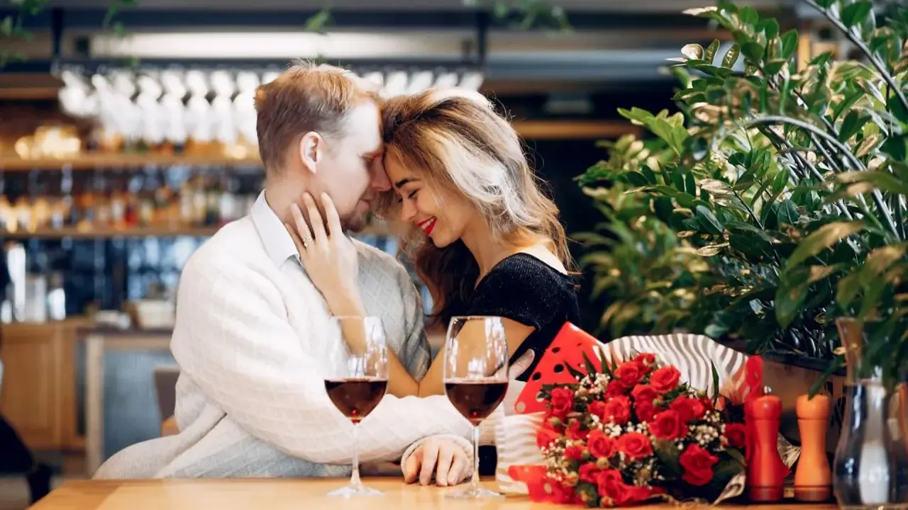 Para świętuje 13 rocznicę ślubu w restauracji, z kieliszkami wina i bukietem czerwonych róż.