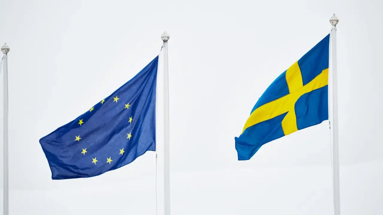 Sveriges flagga och EU-flaggan vajar sida vid sida. En symbol för samarbete inom europeiska unionen.