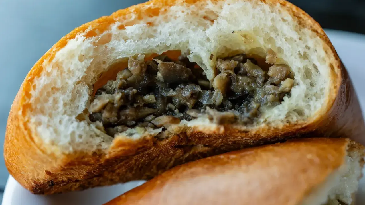 Puszysta bułka z pieczarkami, przekrojona na pół, odsłaniająca aromatyczne, drobno posiekane grzyby.