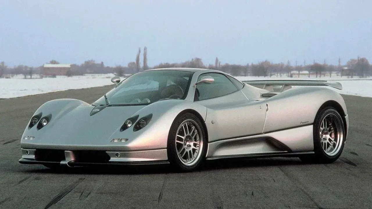 Silberner Pagani Zonda C12 steht auf einer Straße, im Hintergrund verschneite Bäume und Gebäude.