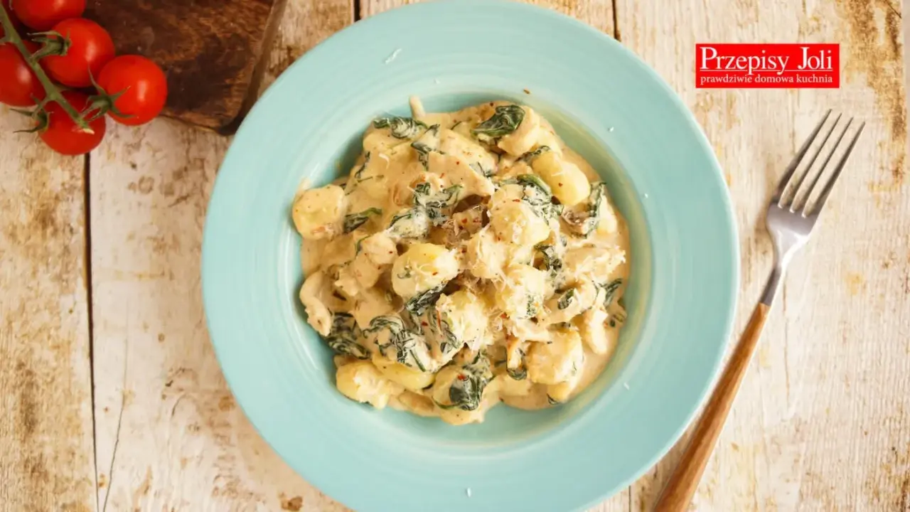 Pyszne gnocchi z kurczakiem i szpinakiem w kremowym sosie, posypane parmezanem. Idealne danie na obiad.