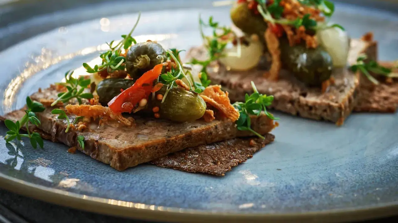 Två bitar mörkt bröd med leverpastej, toppade med cornichoner, chili och krispiga topping. Ett enkelt leverpastej recept att inspireras av.