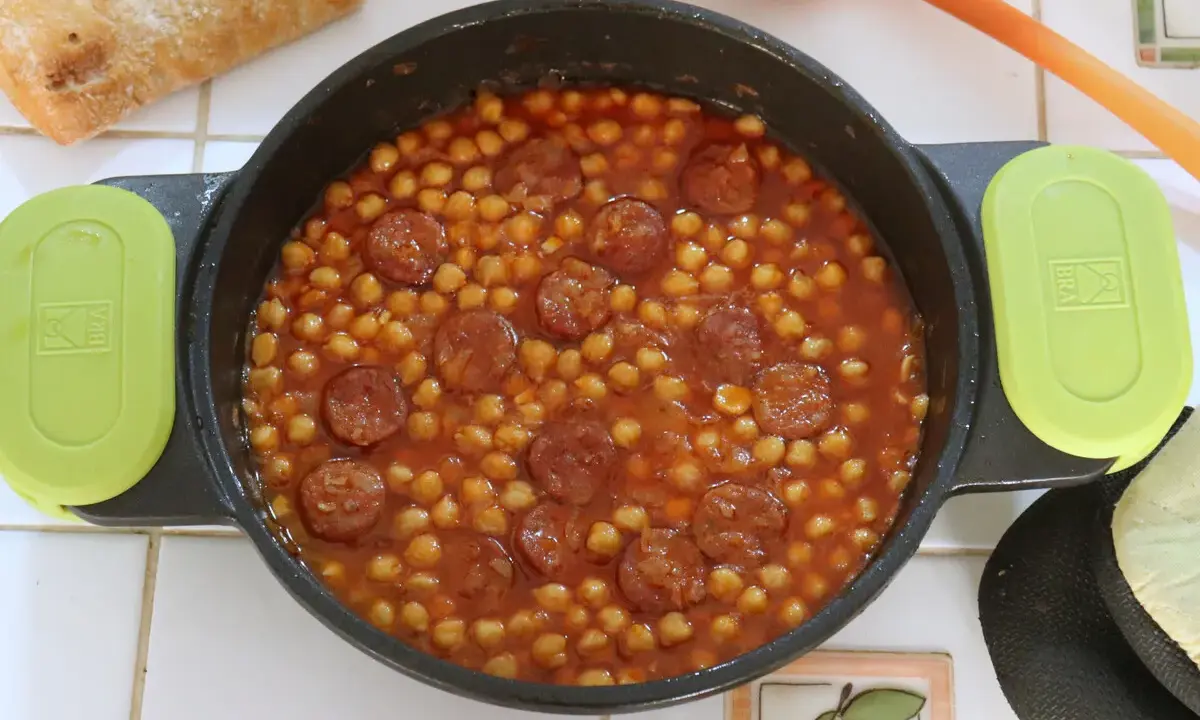 Un plato humeante de garbanzos con chorizo, listo para disfrutar con pan crujiente.