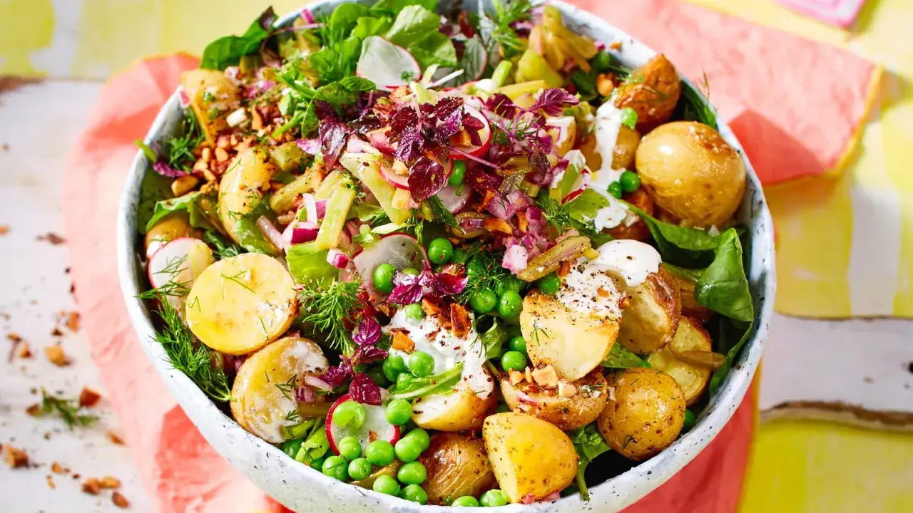 Kartoffelsalat mal anders: Ein bunter Mix aus kleinen Kartoffeln, Erbsen, Radieschen, Zwiebeln und Kräutern in einer Schüssel.